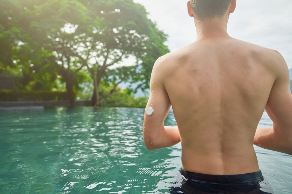 A man wearing a CGM sensor in a pool