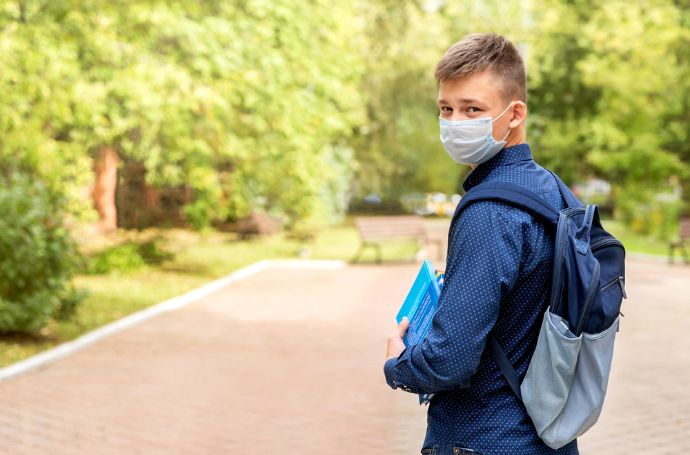 A teen wearing a medical mask outside