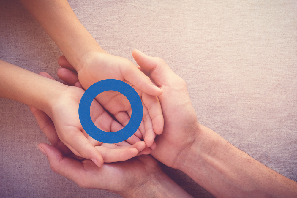 An adult's and a child's hands holding a blue circle