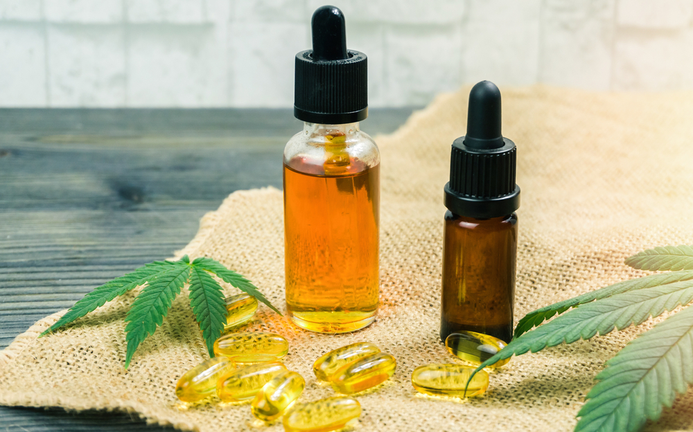 Two vials of cannabidiol sit upon burlap and plant leaves