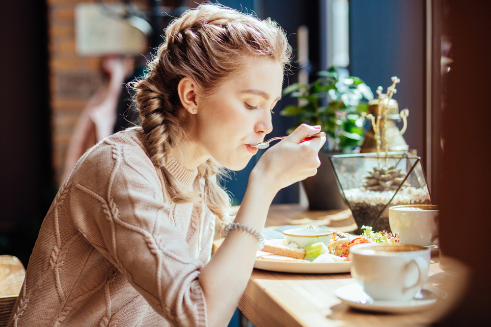 A woman eats at a cafe counter.