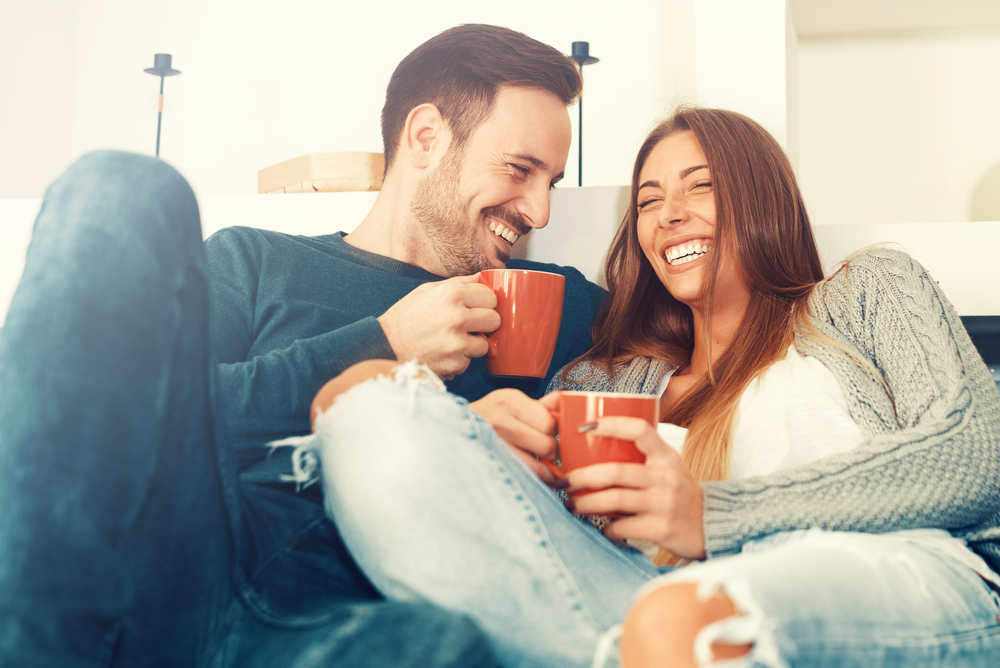 A couple living with type 1 diabetes laugh together with coffee