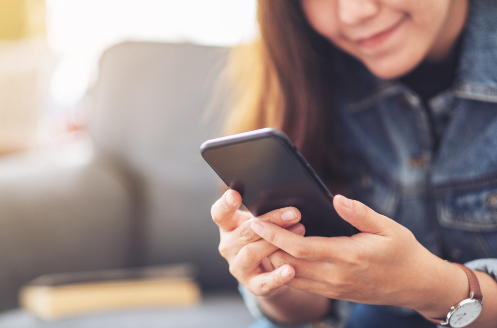 Young woman at home using her smartphone diabetes apps to help manage her type 1 diabetes.