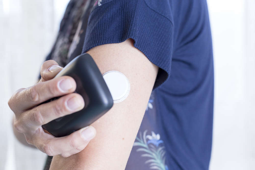 A young woman uses a continuous glucose monitor.