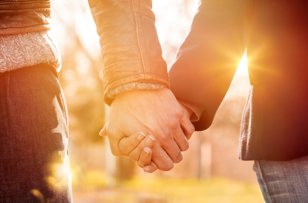 Couple living with type 1 diabetes holds hands while discussing birth control outdoors.