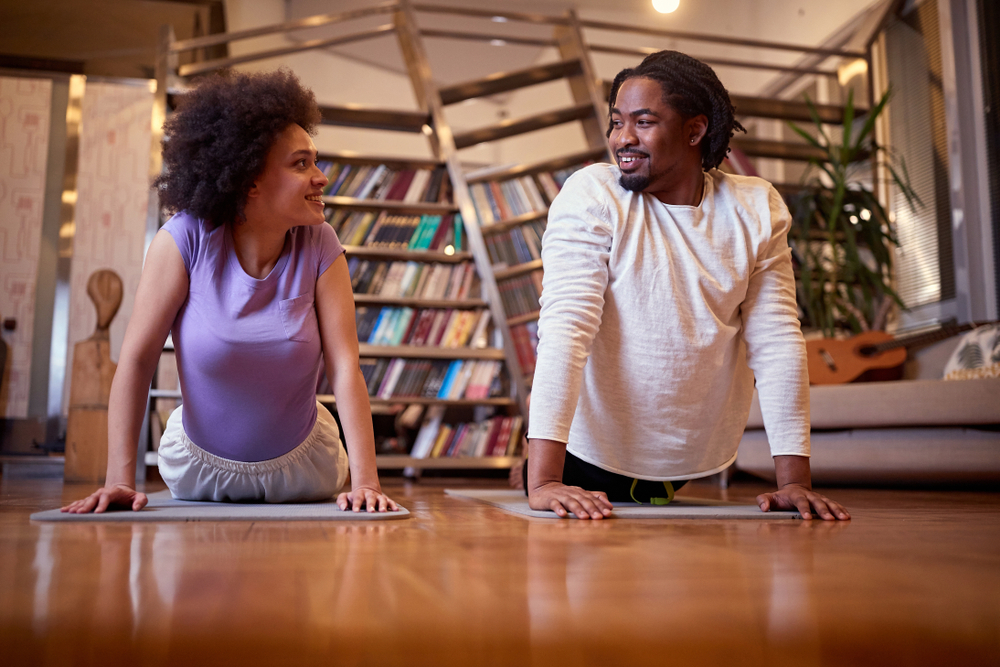 A couple does yoga in their living room.
