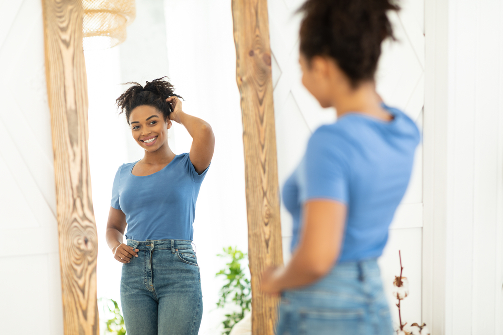 A woman with an insulin pump hidden beneath her clothing smiles as she looks in the mirror