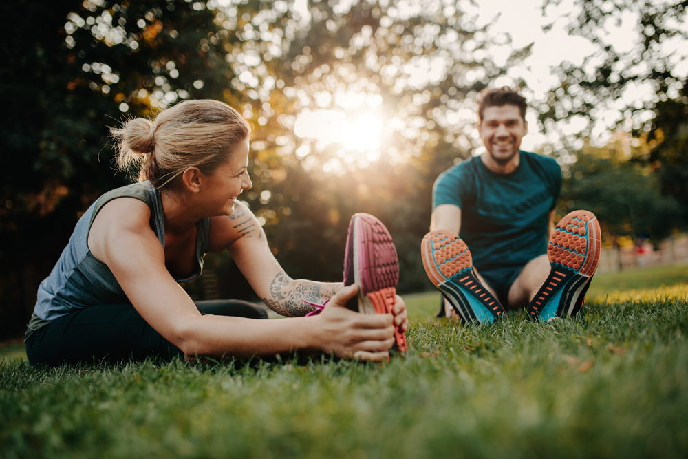 A man and woman stretch their muscles after exercise