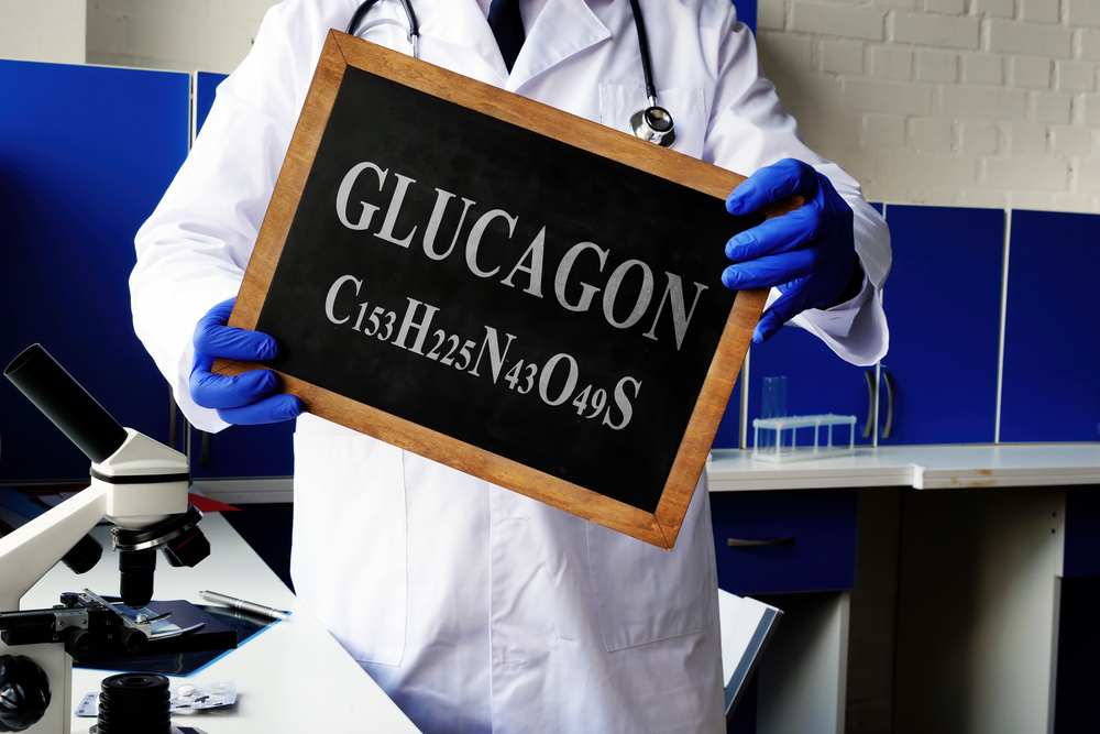 A scientist holds up a chalkboard with glucagon written on it.