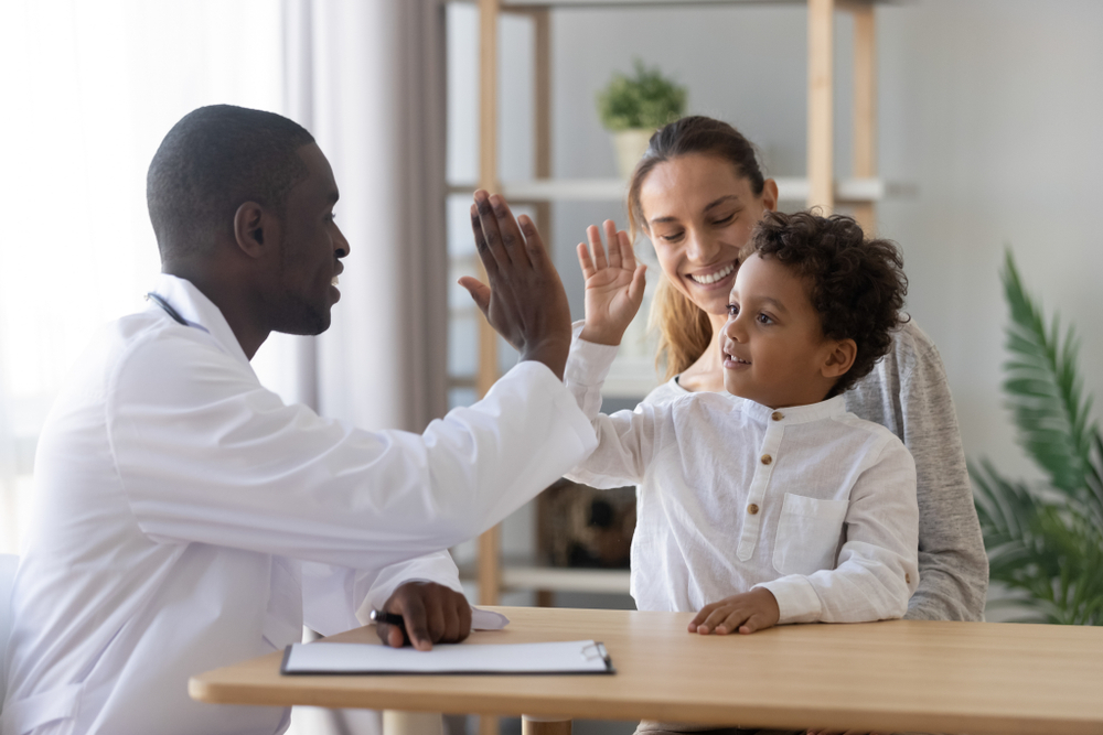 A child high-fiving a doctor
