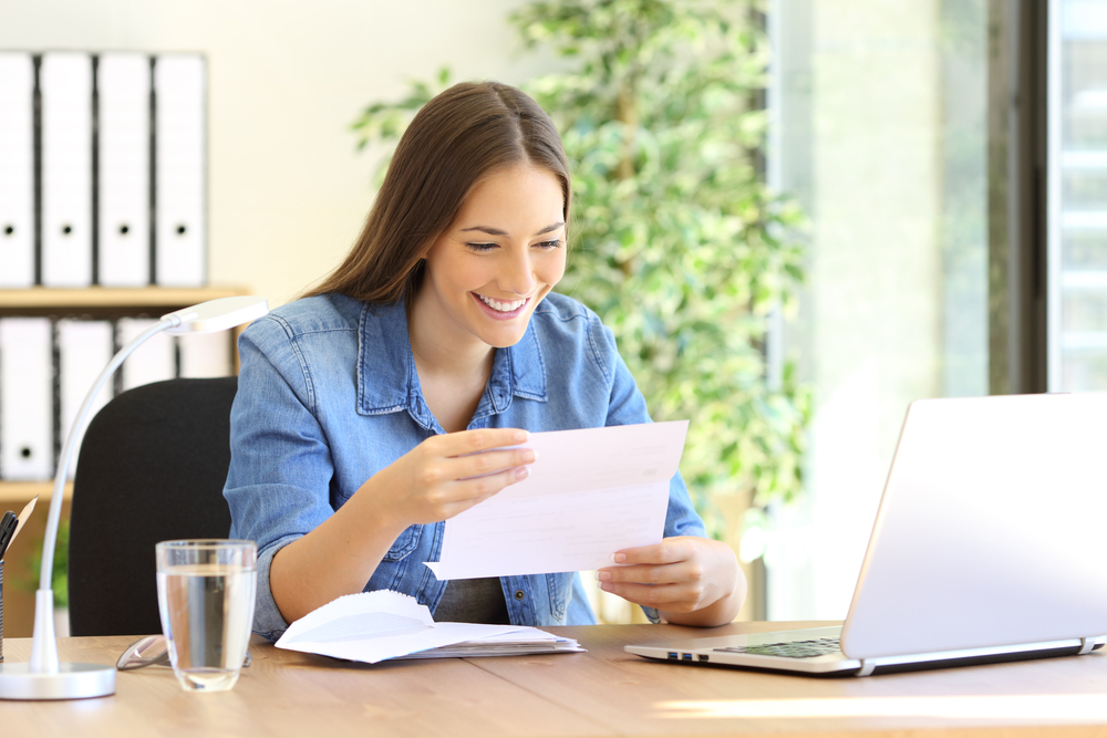 A smiling woman reading a piece of paper