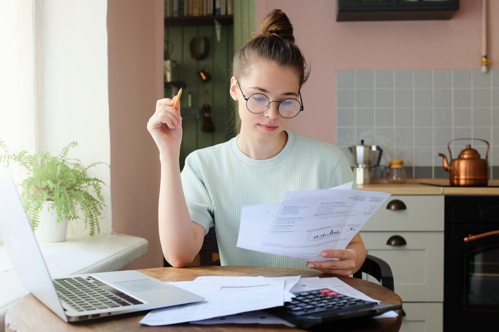 A woman reviews paperwork at her kitchen table