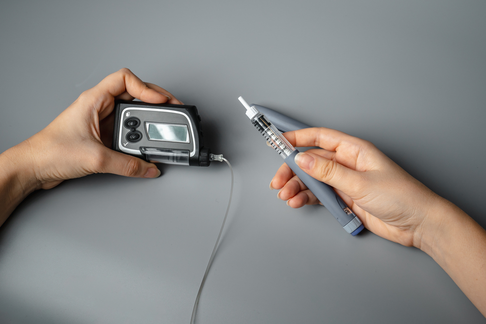 A person holds an insulin pump and a syringe.