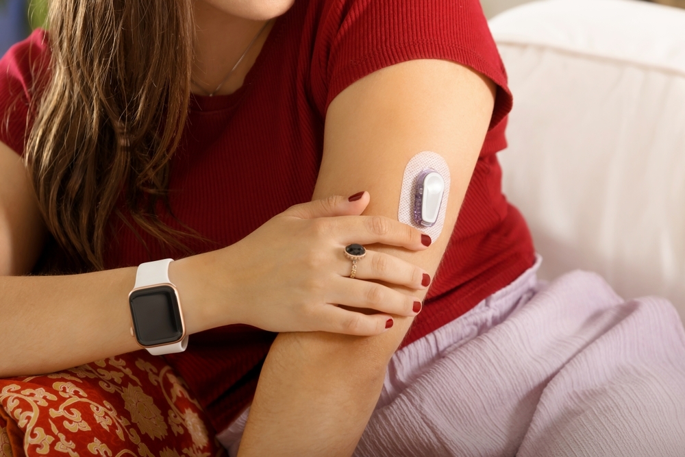 A woman with diabetes examines her continuous glucose monitor site