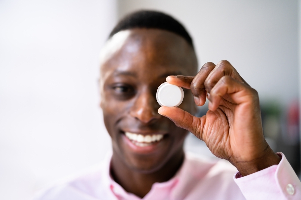 A smiling man holds up a continuous glucose monitor sensor