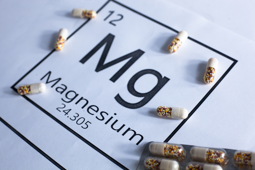 Magnesium capsules lie on top of an image of magnesium on the periodic table.