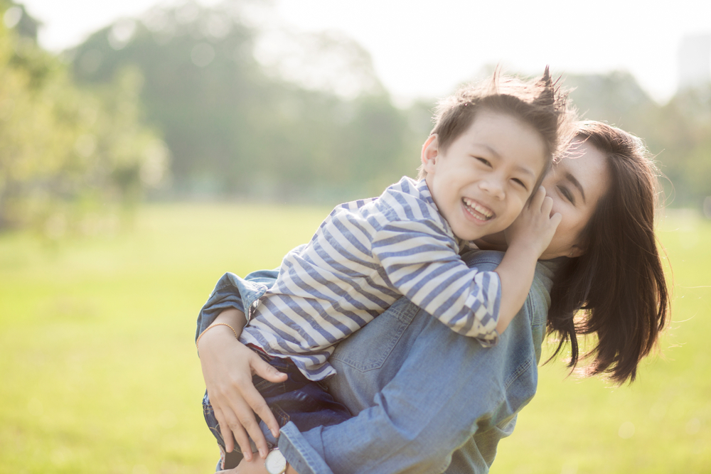Mother and son in a field hugging.