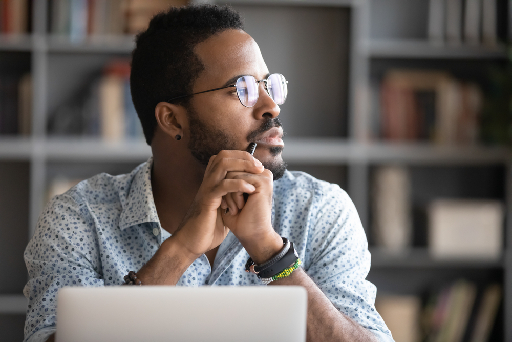 Man with diabetes sitting at desk and starting out of the window because he is distracted by concerns over the coronavirus.
