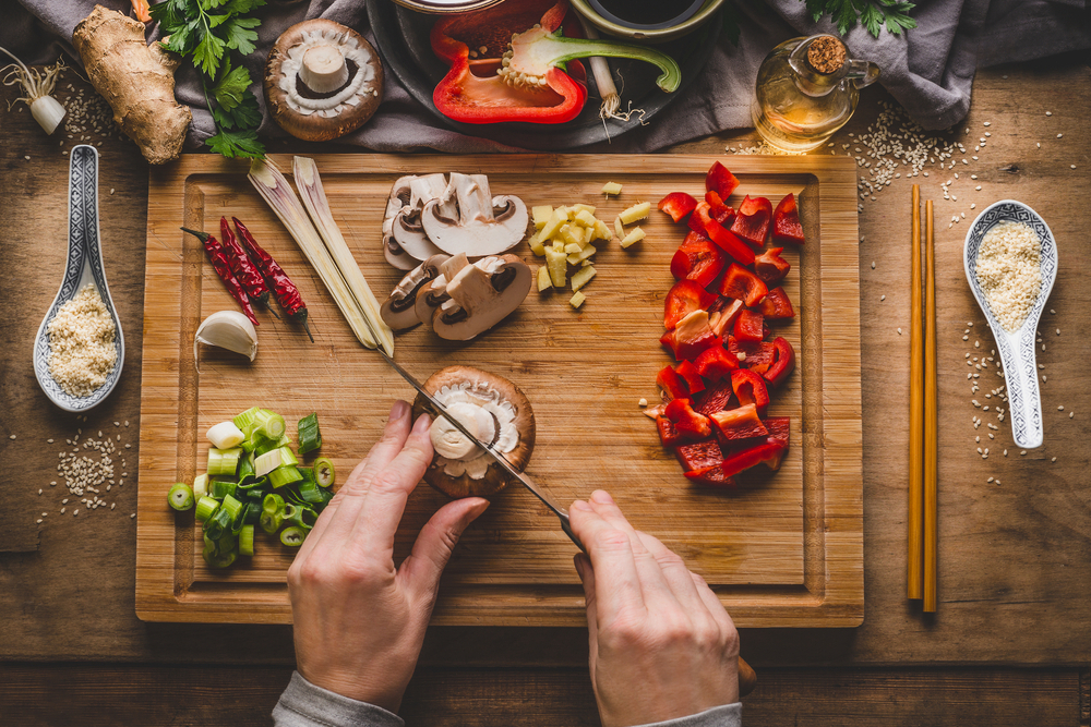A person cuts up mushrooms for a stir fry.