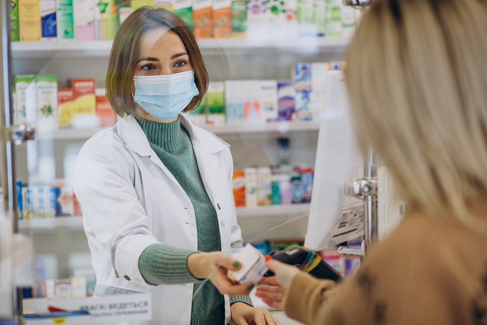 A pharmacist hands a patient her prescription.