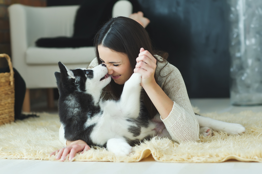 A woman lying on a rug with her dog
