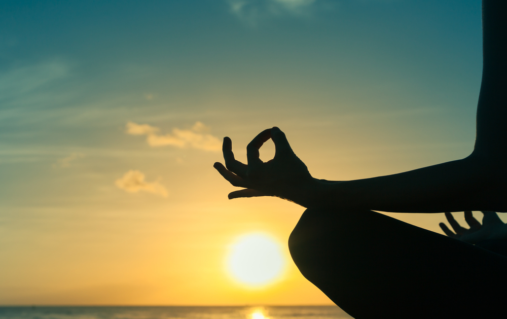Woman meditates as the sun sets