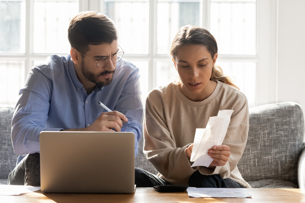 A couple looks at receipts with a laptop.