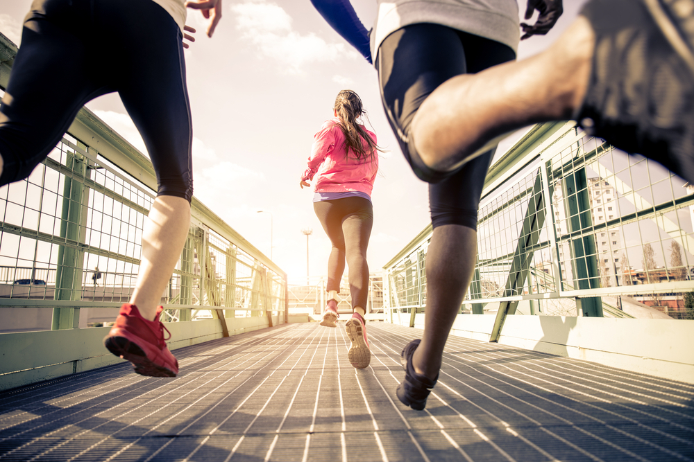 Three people running on a bridge
