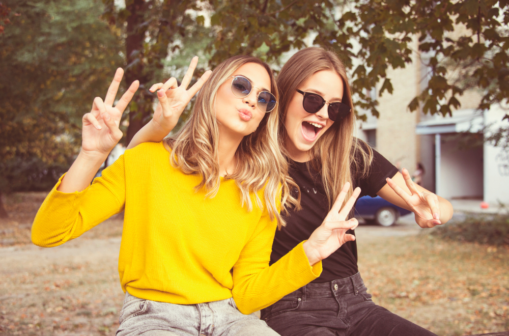 Two college roommates embrace and laugh in the sunshine