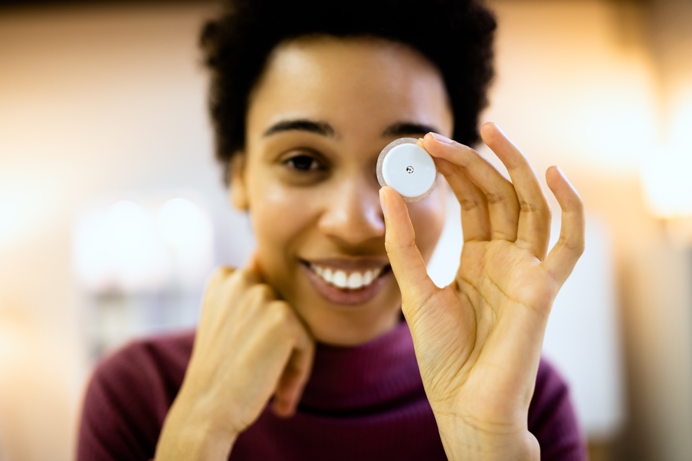 Woman holding a continuous glucose monitor.