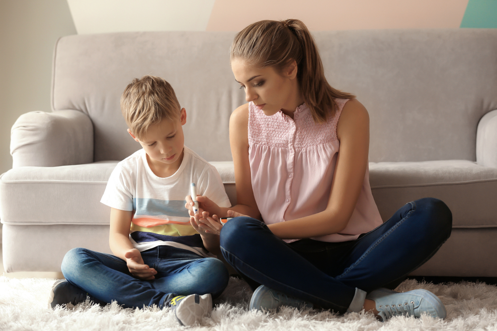 A mother shows her young son how to check his blood glucose.