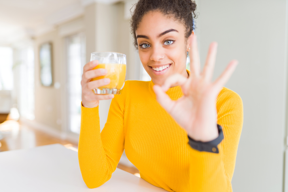 A young woman drinks orange juice to boost her blood sugar levels.