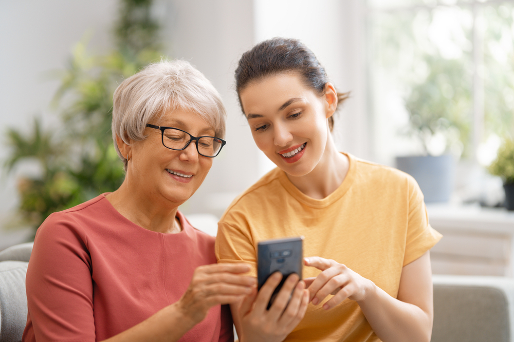 An older woman looks at her phone with her daughter