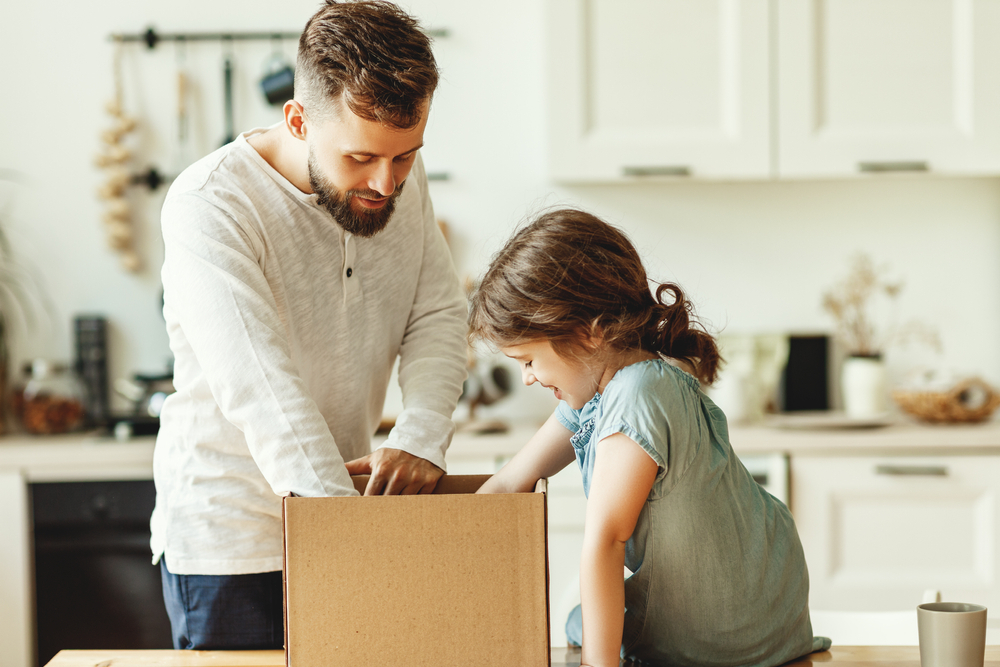 Father and daughter unpacking a box.