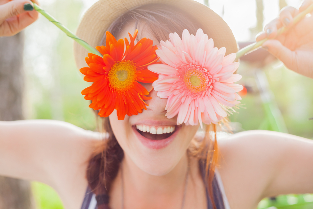 A woman holding two flowers in front of her face