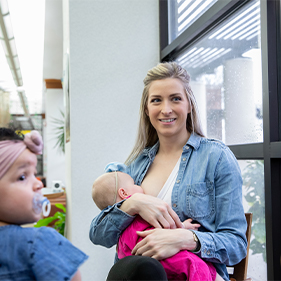 Mother sitting in a chair by the window breastfeeding her baby